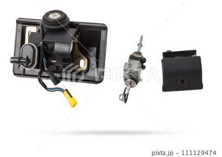 Detail of a car spare part made of black plastic and metal - keyhole lock with key for opening the trunk separately, isolated on a white background. Repair in a car workshop, equipment for sale. Detail of a car spare part made of black plastic and metal - keyhole lock with key for opening the trunk separately, isolated on a white background. Repair in a car workshop, equipment for sale. 111129474