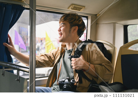 Cheerful Asian man sitting and looking through the bus window. Travel and transportation concept Cheerful Asian man sitting and looking through the bus window. Travel and transportation concept 111131021