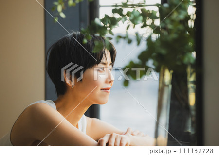 窓辺で夕陽を見る女性 111132728