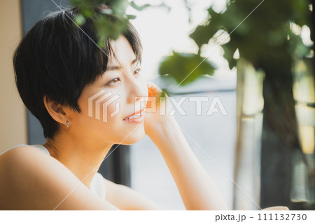 窓辺で夕陽を見る女性 111132730