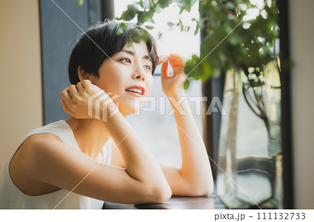 窓辺で夕陽を見る女性 111132733