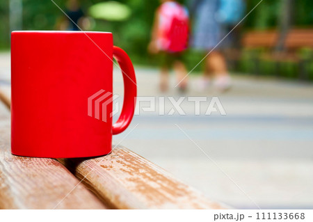 Red ceramic cup on a wooden bench in the park Red ceramic cup on a wooden bench in the park 111133668
