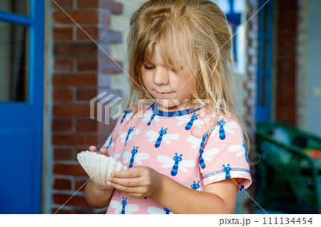 Little preschool girl with variation of different shells and clams at home. Happy child with collected shell from Normandy, France. Children, education, vacation concept. Little preschool girl with variation of different shells and clams at home. Happy child with collected shell from Normandy, France. Children, education, vacation concept. 111134454