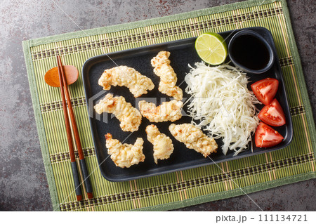 Toriten or Chicken tempura traditional dish of Oita Prefecture with sauce and cabbage salad closeup on the plate. Horizontal top view 111134721