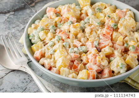 Delicious potato salad with green peas, carrots, corn and apple covered with mayonnaise close-up on a plate. Horizontal 111134743