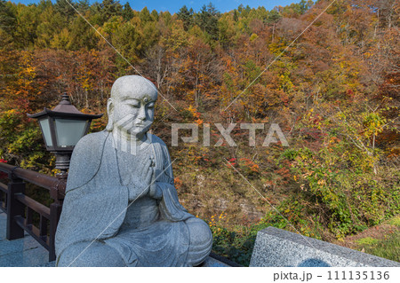 日本 秋田県湯沢市の三途川橋に鎮座している合掌地蔵と紅葉した木々 日本 秋田県湯沢市の三途川橋に鎮座している合掌地蔵と紅葉した木々 111135136