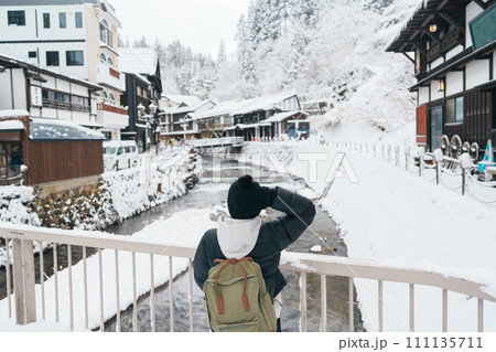 Woman tourist Visiting Ginzan Onsen in Yamagata, happy Traveler sightseeing Japanese Onsen village with Snow in winter season. landmark and popular for attraction in Japan. Travel and Vacation concept 111135711