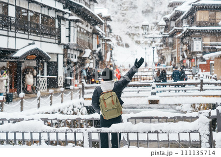 Woman tourist Visiting Ginzan Onsen in Yamagata, happy Traveler sightseeing Japanese Onsen village with Snow in winter season. landmark and popular for attraction in Japan. Travel and Vacation concept Woman tourist Visiting Ginzan Onsen in Yamagata, happy Traveler sightseeing Japanese Onsen village with Snow in winter season. landmark and popular for attraction in Japan. Travel and Vacation concept 111135714