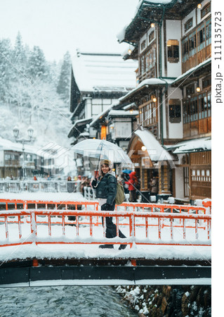 Woman tourist Visiting Ginzan Onsen in Yamagata, happy Traveler sightseeing Japanese Onsen village with Snow in winter season. landmark and popular for attraction in Japan. Travel and Vacation concept Woman tourist Visiting Ginzan Onsen in Yamagata, happy Traveler sightseeing Japanese Onsen village with Snow in winter season. landmark and popular for attraction in Japan. Travel and Vacation concept 111135723