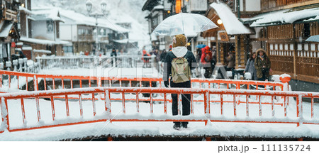 Woman tourist Visiting Ginzan Onsen in Yamagata, happy Traveler sightseeing Japanese Onsen village with Snow in winter season. landmark and popular for attraction in Japan. Travel and Vacation concept Woman tourist Visiting Ginzan Onsen in Yamagata, happy Traveler sightseeing Japanese Onsen village with Snow in winter season. landmark and popular for attraction in Japan. Travel and Vacation concept 111135724