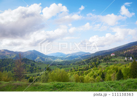 natural beauty of the ukrainian mountainous rural landscape in spring. alpine countryside scenery with grassy rolling hills in evening light. mountain ridge in the distance beneath a sky with clouds natural beauty of the ukrainian mountainous rural landscape in spring. alpine countryside scenery with grassy rolling hills in evening light. mountain ridge in the distance beneath a sky with clouds 111138363
