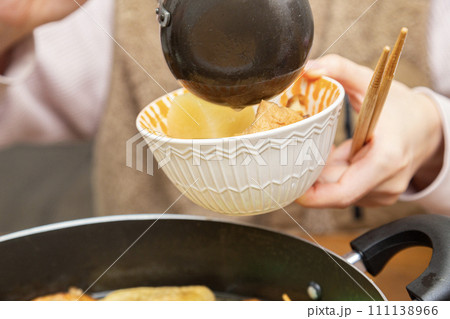 お玉でおでんの出汁をお皿に入れる 111138966