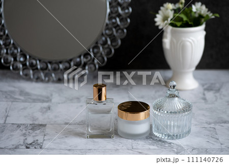 大理石の上に丸い鏡と美容液とクリームを配置した夜のスキンケアイメージ 111140726