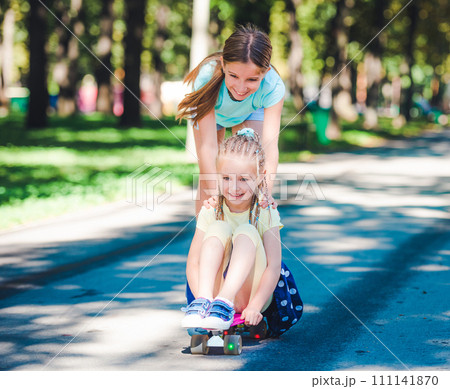 Smiling kids joyfully riding on skateboard in sunshine park Smiling kids joyfully riding on skateboard in sunshine park 111141870
