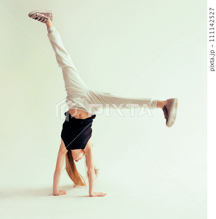 Attractive flexible teenage girl doing handstand on light background 111142527