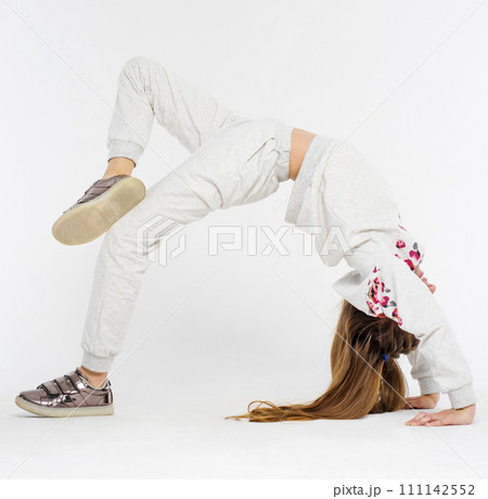 Little active gymnast girl do bridge position on light background Little active gymnast girl do bridge position on light background 111142552
