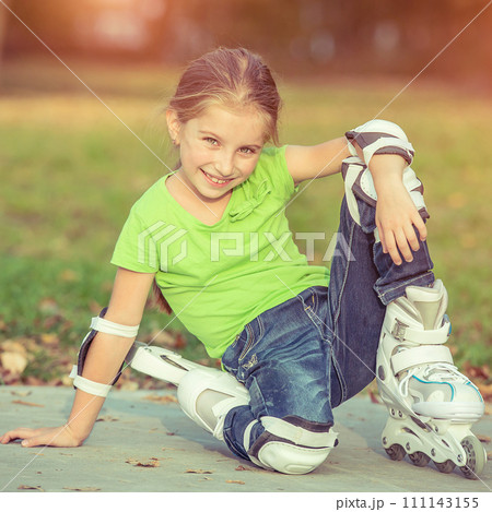 Little girl on roller skates sitting in park 111143155
