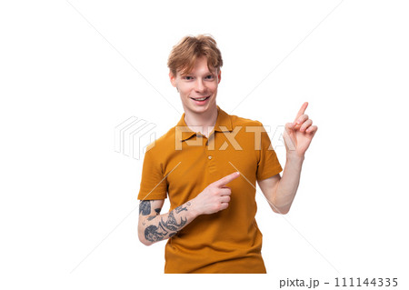 a young guy with short red hair dressed in a summer T-shirt points to the side with his hand a young guy with short red hair dressed in a summer T-shirt points to the side with his hand 111144335