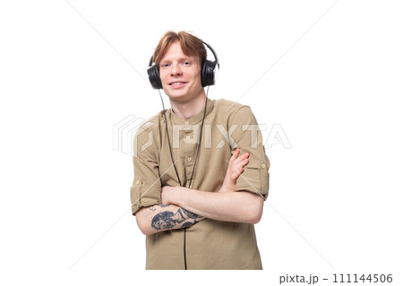 young red-haired guy in glasses and a brown shirt listens to music on headphones 111144506