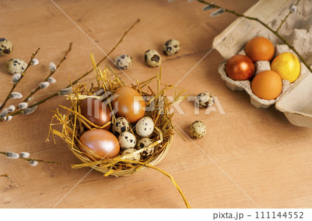Painted Easter eggs lie in wicker basket on wooden tabletop. are spring flowers 111144552