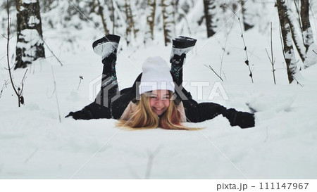 A girl falls on the snow in winter in the forest. A girl falls on the snow in winter in the forest. 111147967
