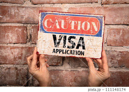 VISA Application. Caution sign in a woman's hand on a brick background VISA Application. Caution sign in a woman's hand on a brick background 111148174