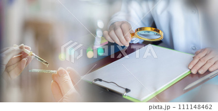 A doctor examines documents with a magnifying glass. A doctor examines documents with a magnifying glass. 111148462