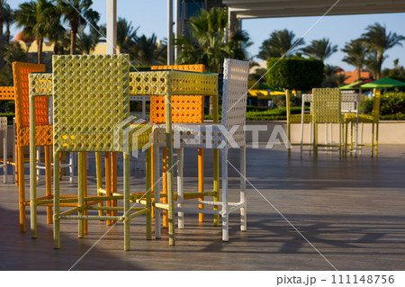 Dining table in a summer outdoor cafe with wicker furniture against the backdrop of an exotic park with palm trees in Egypt 111148756