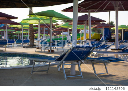 Equipped place to relax under an umbrella by the pool, sun lounger hidden in the shade from the sun on vacation at the hotel 111148806