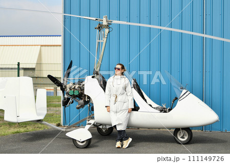 A woman near two-seater white gyrocopter A woman near two-seater white gyrocopter 111149726