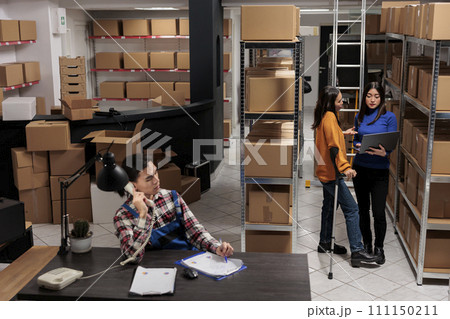 Delivery operators managing warehouse product audit in storage room. Retail industry storehouse employees working together, tracking parcel transportation online on laptop 111150211