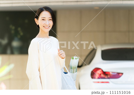自宅の前で買い物袋を持つ女性 111151016