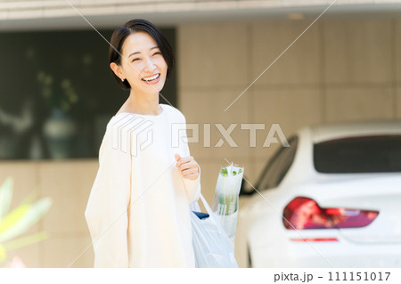 自宅の前で買い物袋を持つ女性 111151017