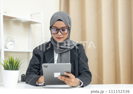 Young muslim beautiful businesswoman wear hijab using tablet business thinking about work. Young muslim beautiful businesswoman wear hijab using tablet business thinking about work. 111152536