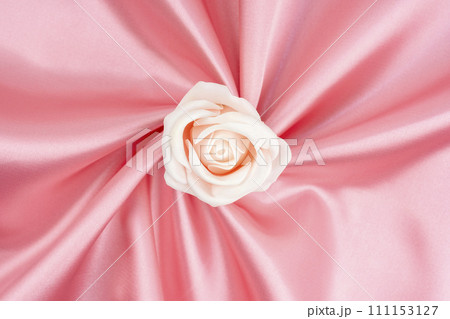 Pink satin fabric texture background with rose flower is center position. 111153127