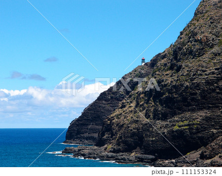 Makapu'u Lighthouse on cliffside mountain top with stretching blue pacific ocean below 111153324