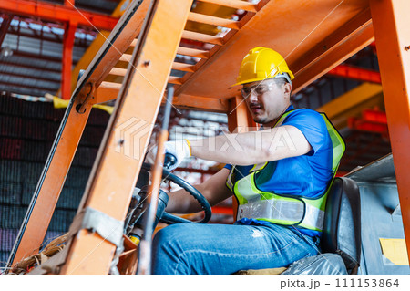 Worker wearing safety uniform drive forklift move product iron metal on shelves in warehouse. 111153864