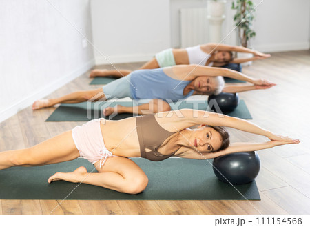 Family of three generations doing soft ball pilates exercises during group pilates class in studio Family of three generations doing soft ball pilates exercises during group pilates class in studio 111154568