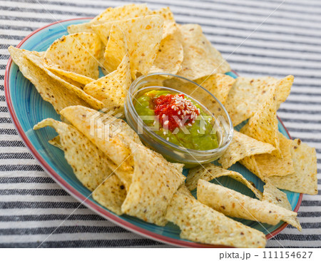 Chips nachos with sauces on colored dish Chips nachos with sauces on colored dish 111154627