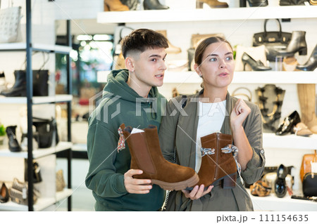 Guy male friend strongly recommends his young woman colleague to pay attention to model of boots Guy male friend strongly recommends his young woman colleague to pay attention to model of boots 111154635