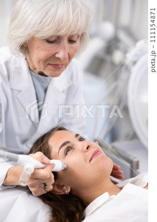 Young woman having face vacuum cleaning procedure Young woman having face vacuum cleaning procedure 111154871