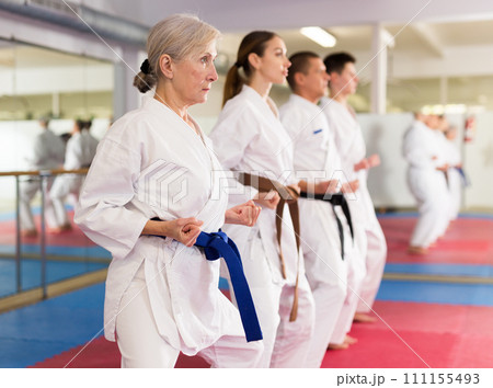 People practicing taekwondo and warming up for training while standing barefoot People practicing taekwondo and warming up for training while standing barefoot 111155493