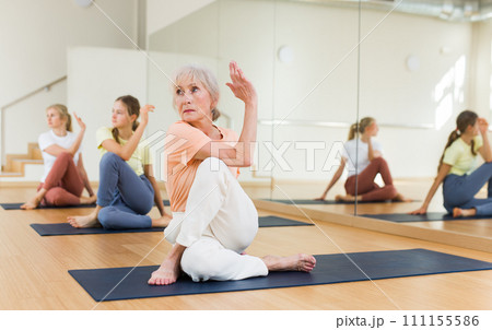 Elderly woman training yoga with her family Elderly woman training yoga with her family 111155586