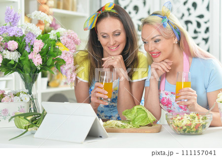 Two beautiful young women cooking together in kitchen Two beautiful young women cooking together in kitchen 111157041