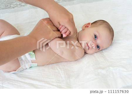 Mother's hands do gymnastics with the baby. Arms crossed on chest 111157630
