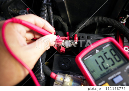Car battery voltage testing with a digital multimeter by auto technician Car battery voltage testing with a digital multimeter by auto technician 111158773
