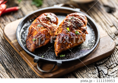 Marinated grilled chicken breast in BBQ sauce and served on a cast iron pan - Close up 111159953