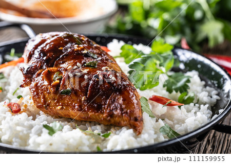 Grilled chicken breast served in a pan with jasmine rice and chili peppers 111159955