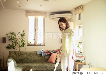 掃除機でリビングの掃除をするミドル女性 111160337