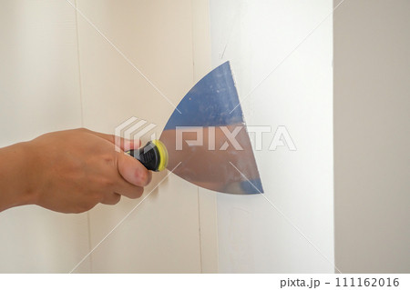 Man repairing crack white wall with spatula 111162016